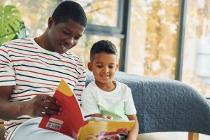 African American father with his young son at home, reading