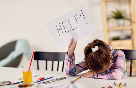 Small girl feeling desperate and holding HELP sign while homeschooling