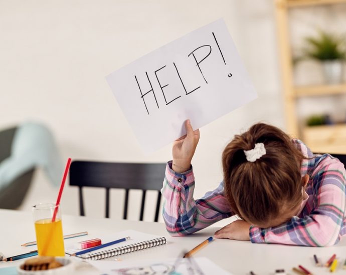 Small girl feeling desperate and holding HELP sign while homeschooling