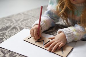 A girl using a block to write a letter.