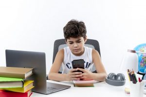 A boy playing with his cellphone while studying