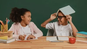 A girl and boy goofing around with educational supplies