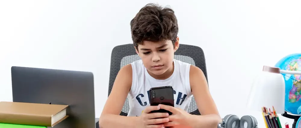 Schoolboy sitting and looking at phone