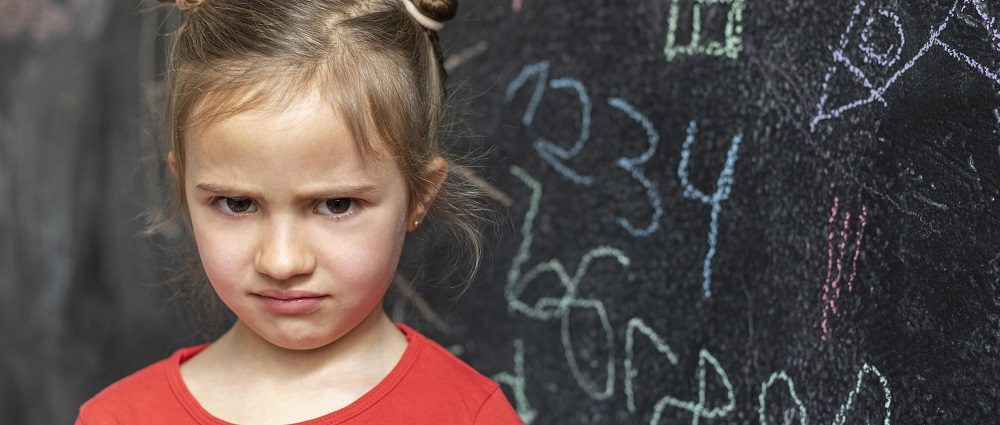 A girl upset in front of blackboard showing math