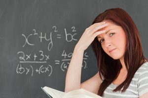 Thoughtful woman trying to solve an equation in a classroom