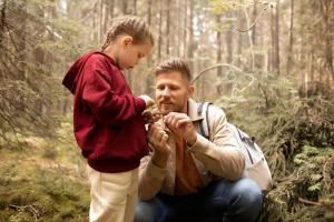 A father and a girl looking at a pine cone